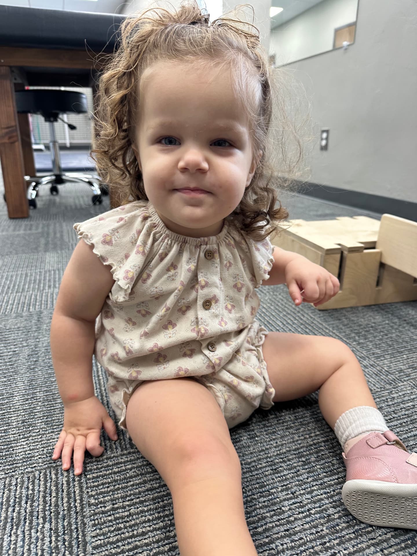 River sitting independently on the clinic floor, smiling.