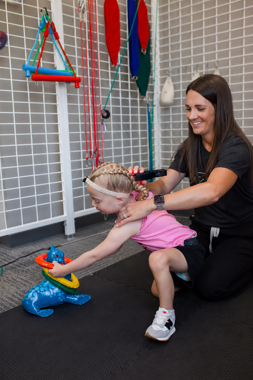 A therapist gently supporting a young child during a reflex integration assessment.