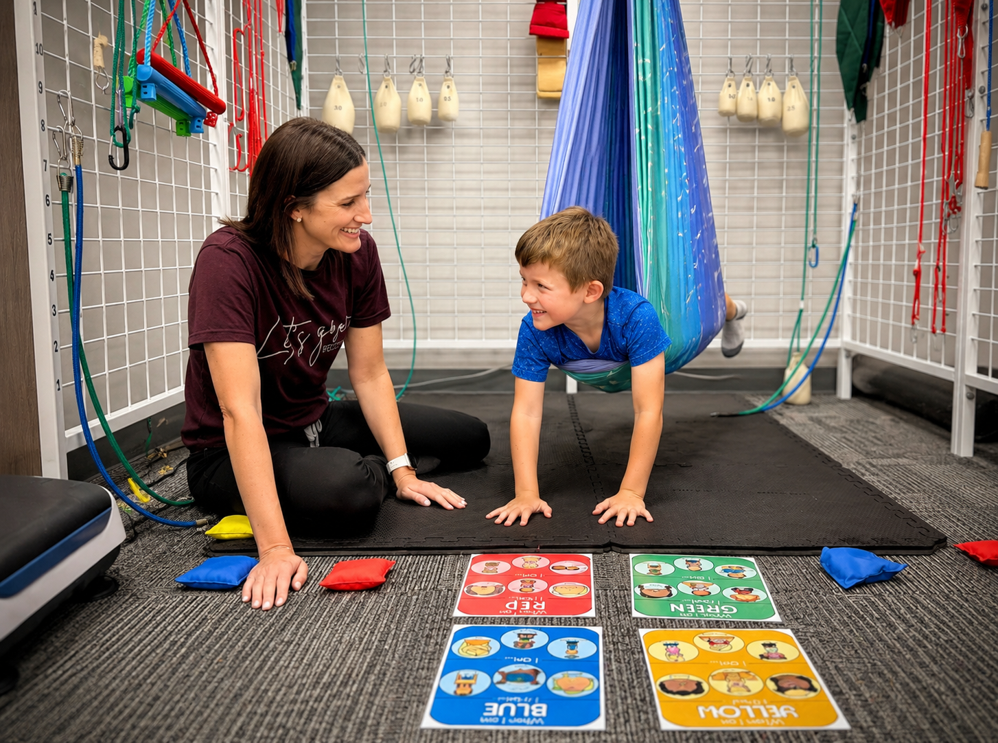Two young children sitting close together on the therapy room floor, engaged with a tablet during a calm regulation activity.