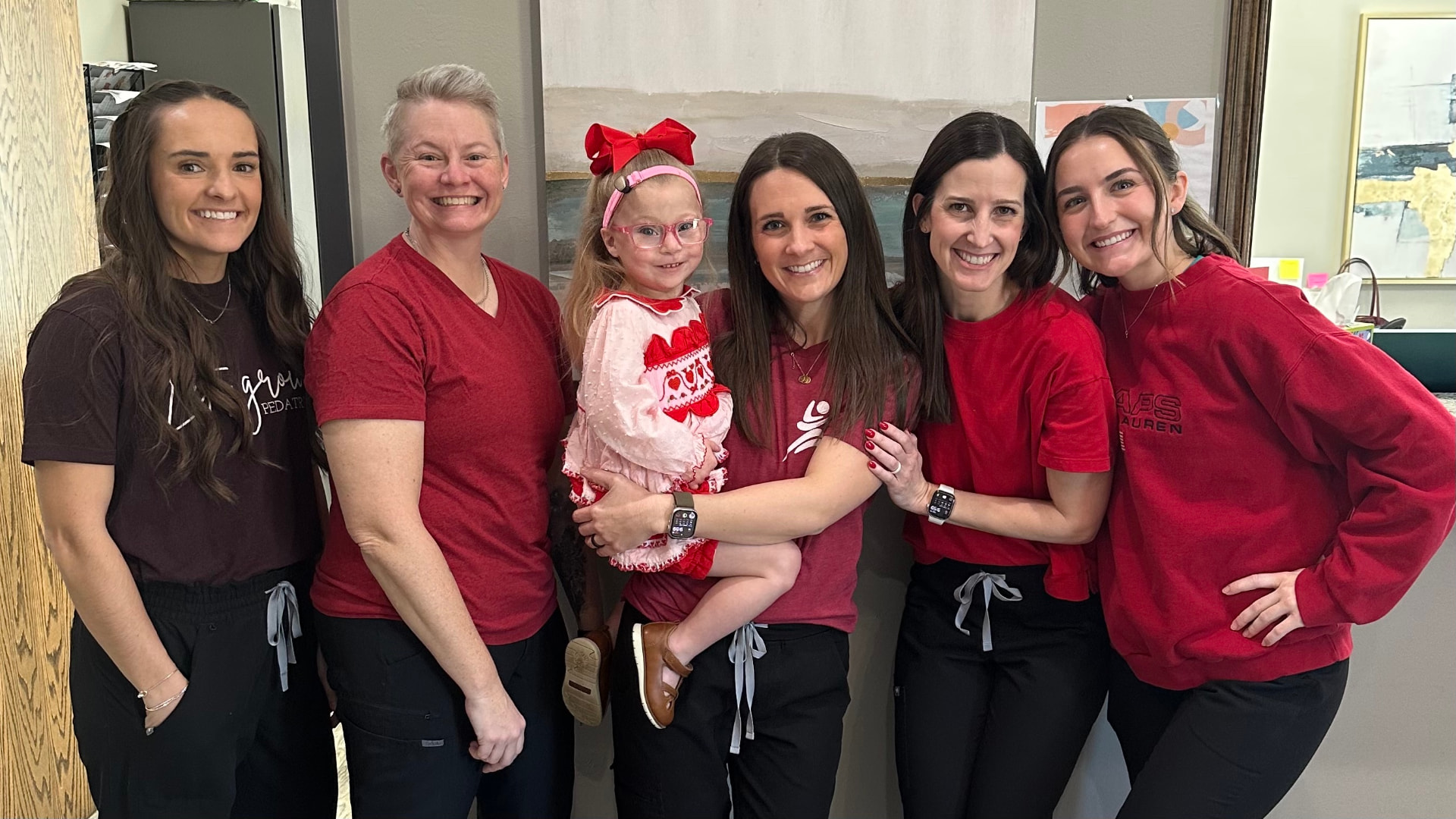 The Let's Grow Pediatrics team gathered with a child in a warm, welcoming moment.