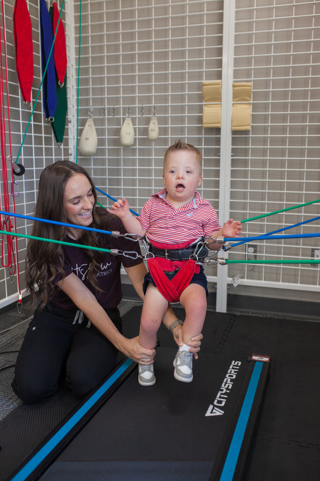 A smiling child working with elastic supports inside a Universal Exercise Unit.